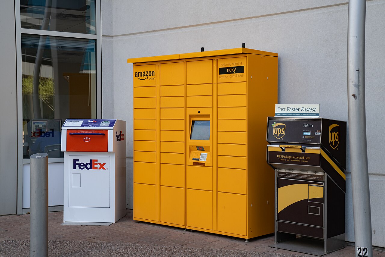 Amazon pickup locker next to FedEx and UPS drop boxes, part of the frictionless delivery infrastructure that makes impulse buying easier
