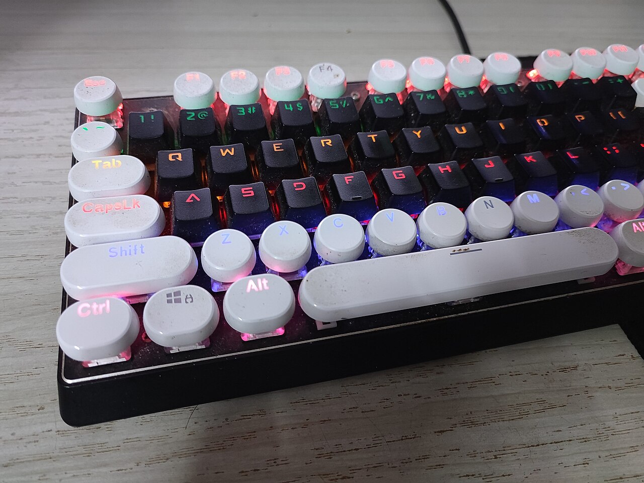Backlit mechanical keyboard with retro round keycaps on a desk