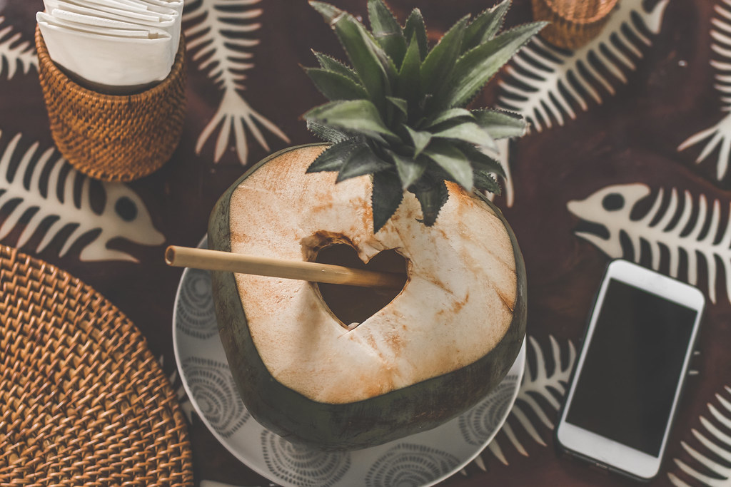 A smartphone resting on a table in the summer heat beside a coconut drink