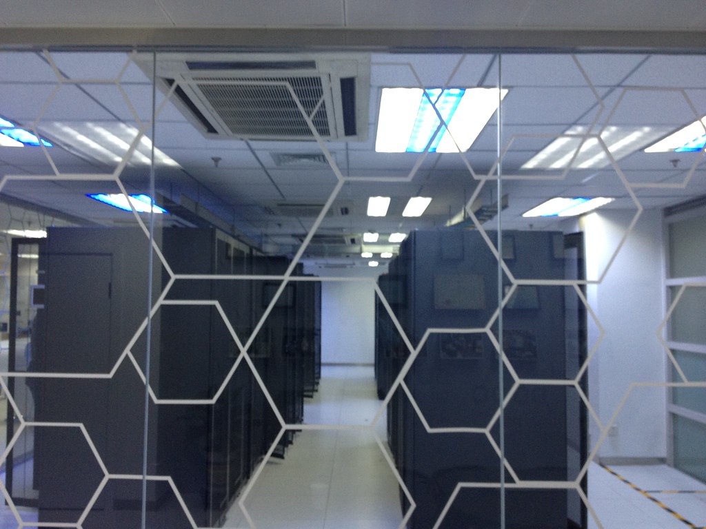 Data center server racks behind a glass partition, representing the large-scale compute infrastructure used to train and run models like Kimi K3