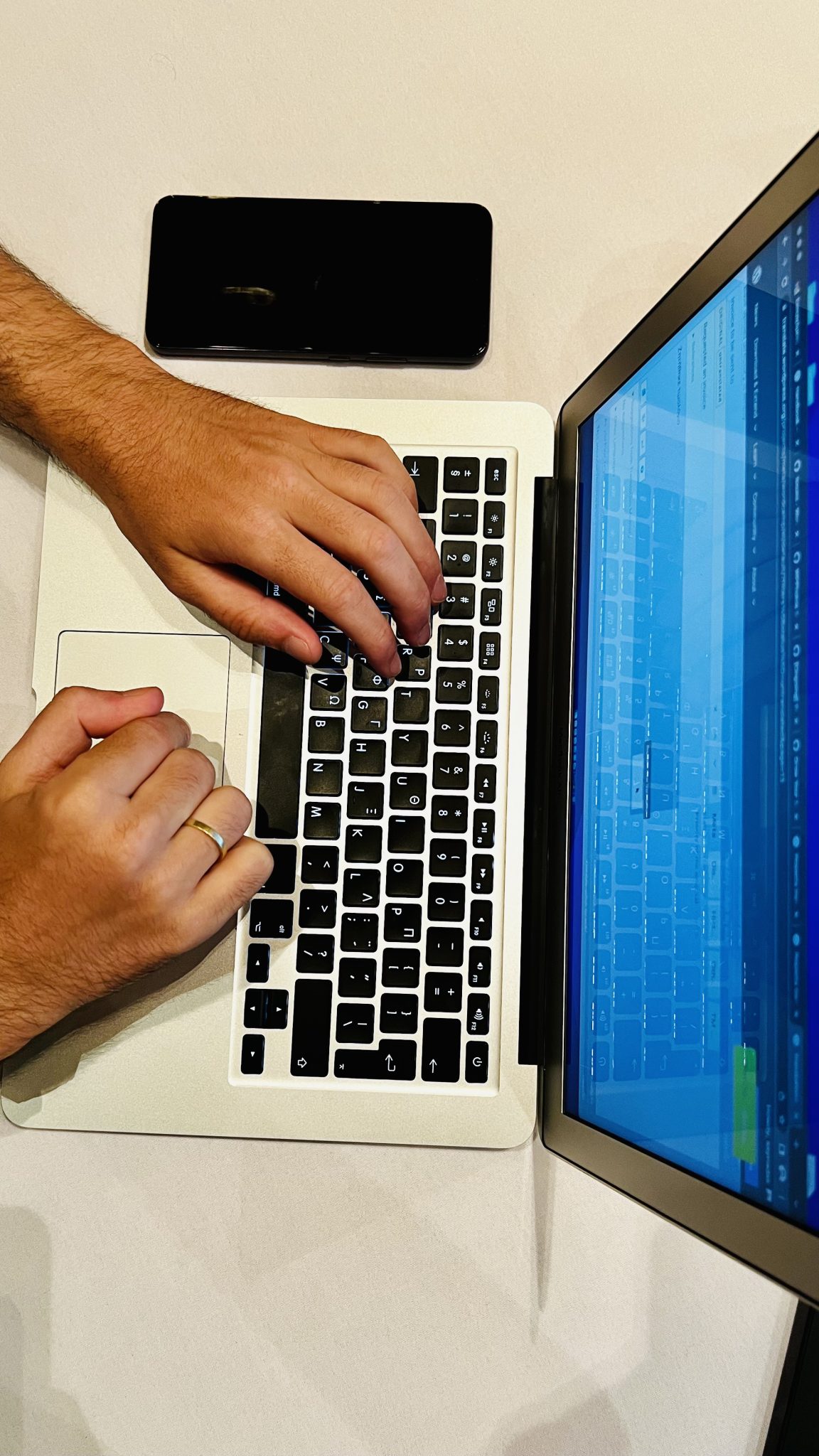Person typing on a laptop with a browser window open next to a smartphone, illustrating everyday AI browser agent use