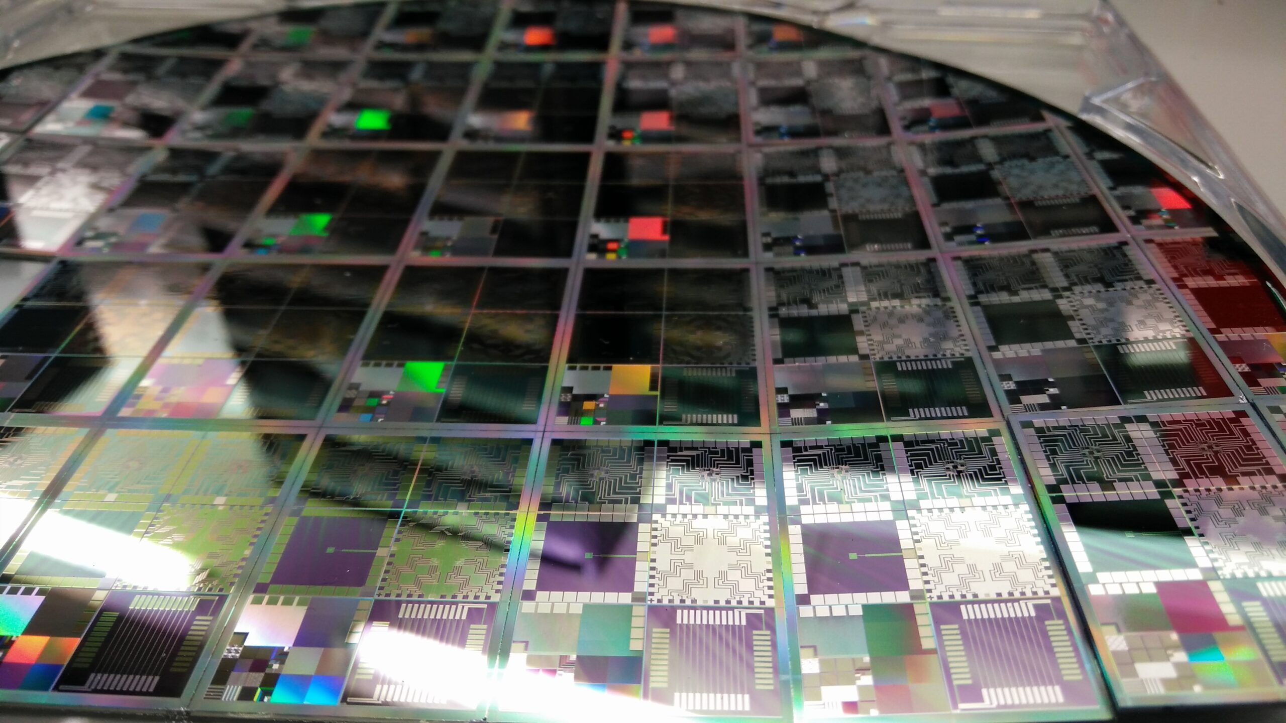 Macro photo of a semiconductor wafer showing individual chip dies, illustrating the silicon wafer capacity behind why is gddr memory expensive 2026