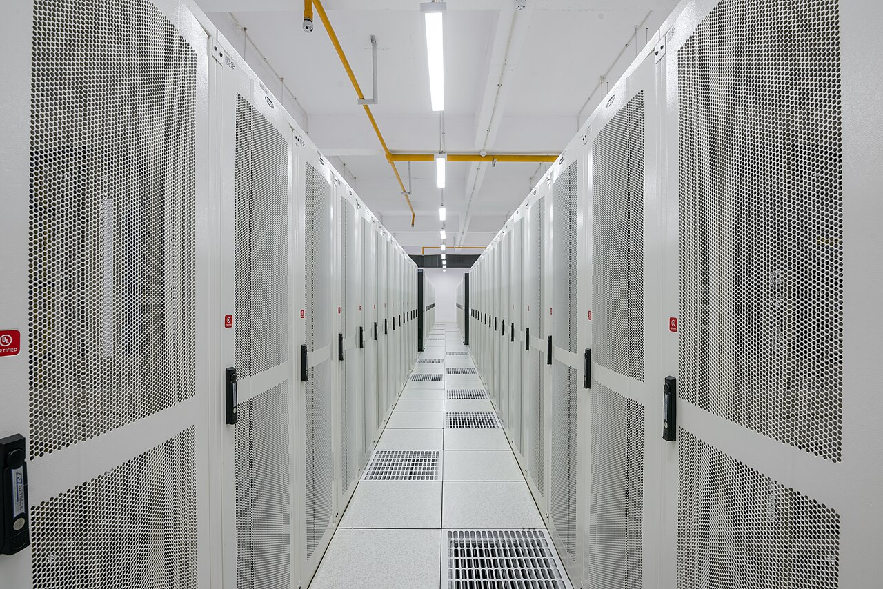 Row of server racks in a modern data center corridor, illustrating the scale of the Ohio data center campus behind the Nvidia-OpenAI deal
