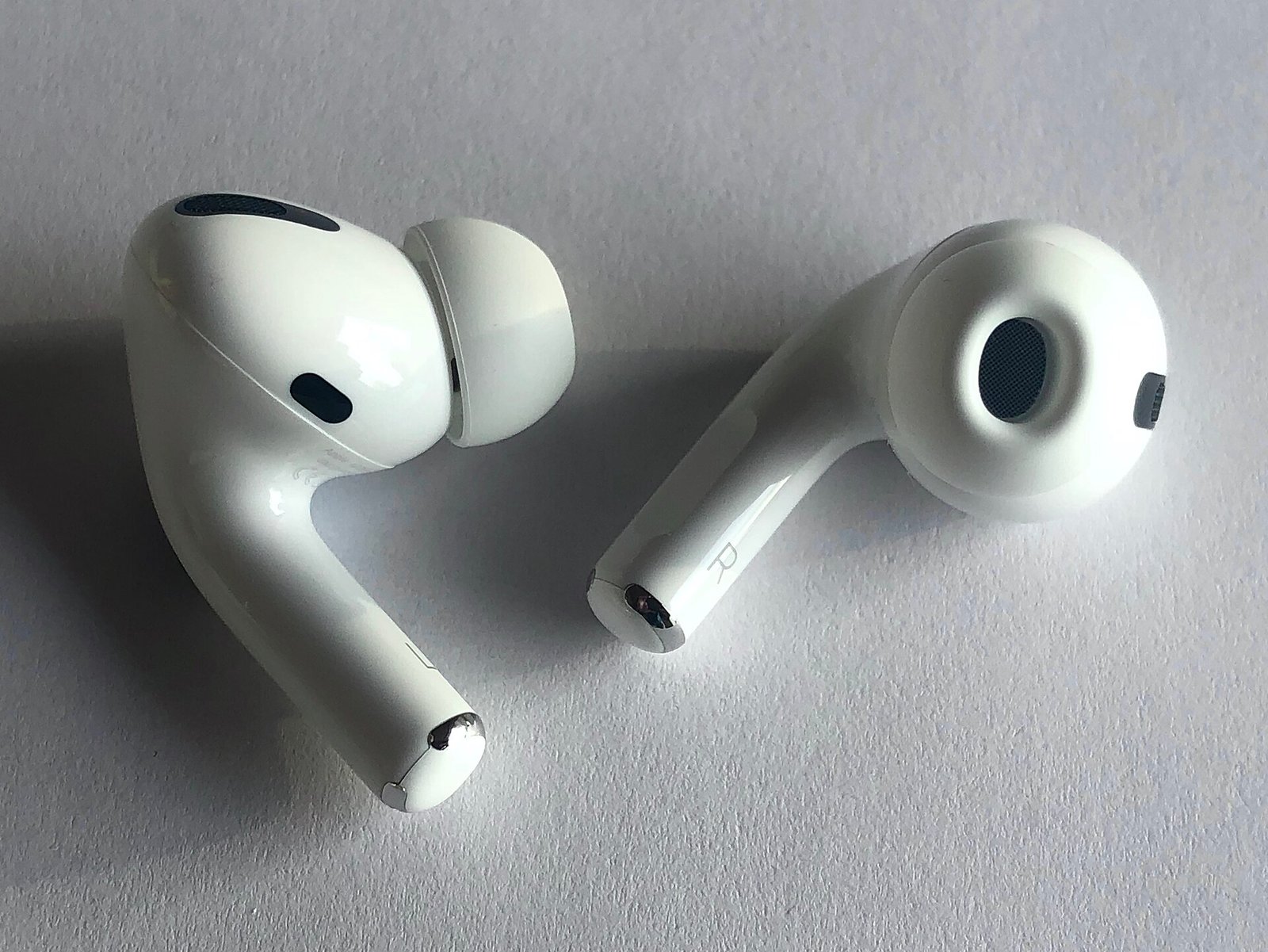 Close-up angled view of Apple AirPods Pro earbuds showing the silicone ear tips and stem design referenced in the macOS Tahoe 26.7 leak
