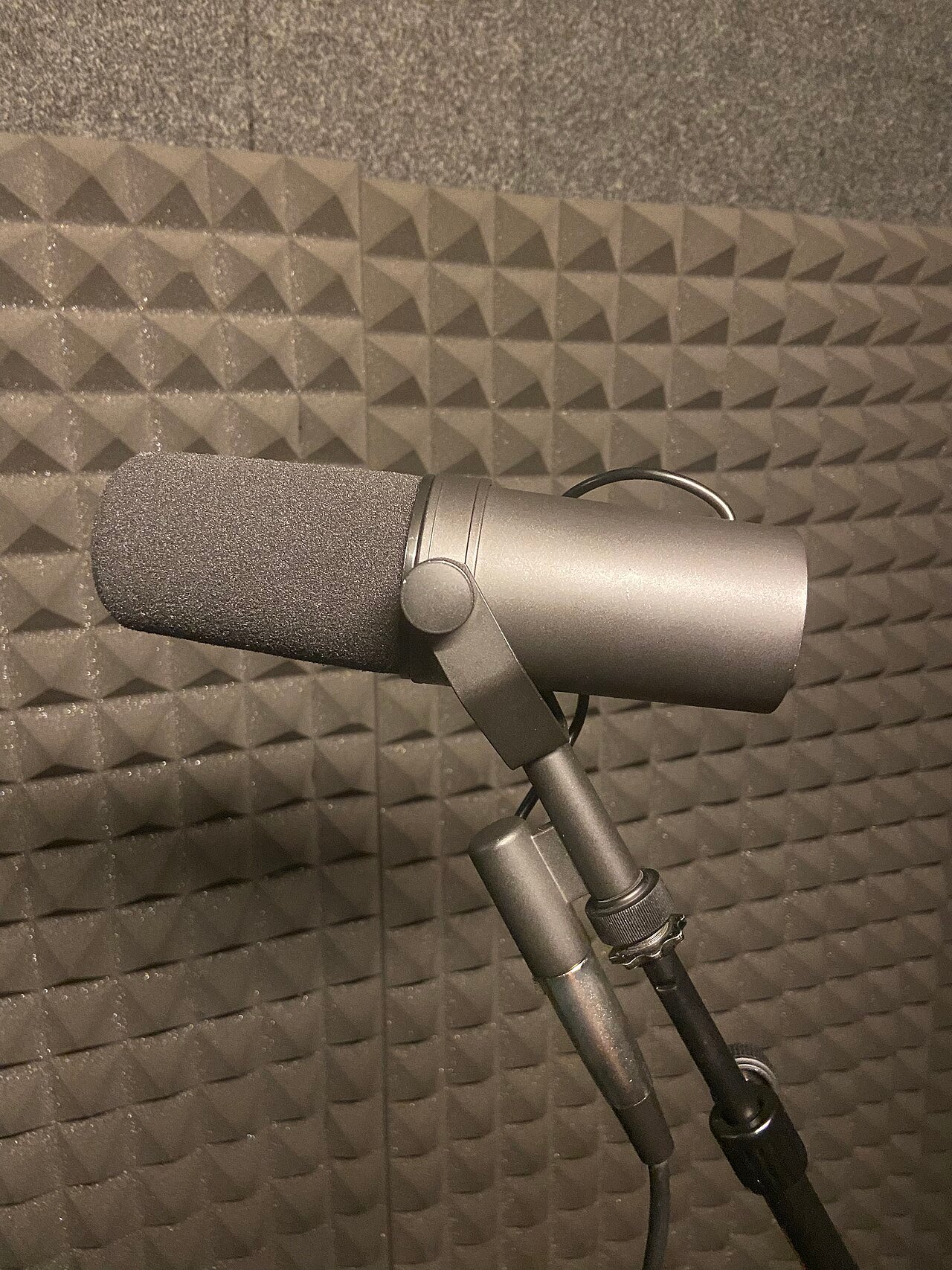 Dynamic podcast microphone with cardioid pattern in front of acoustic foam treatment